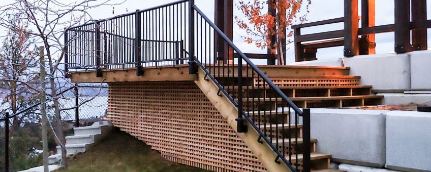 Fascia mount black picket railing installed on a deck and outdoor staircase