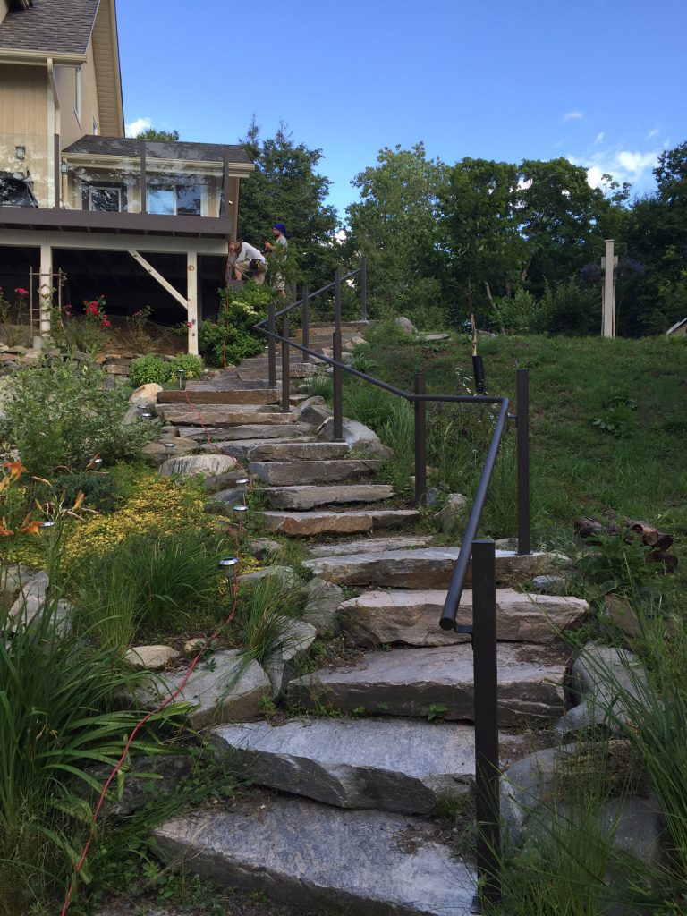 Black pipe railing for an outdoor staircase made with natural rocks