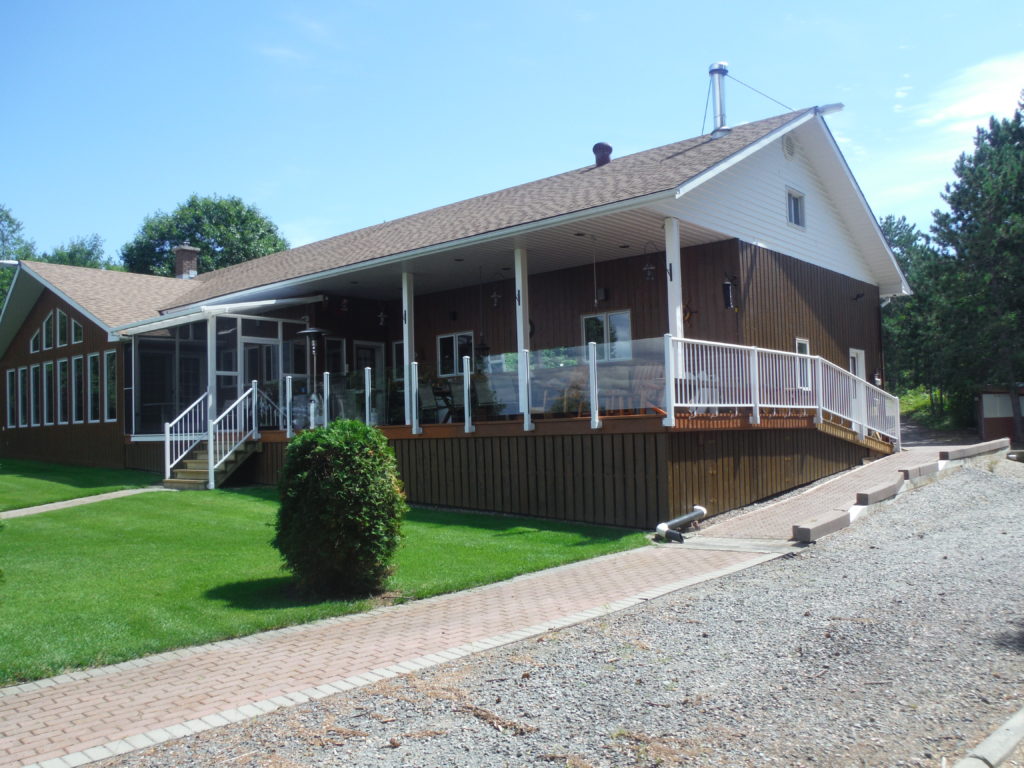 A brown house with white aluminum & glass fascia mount deck railings