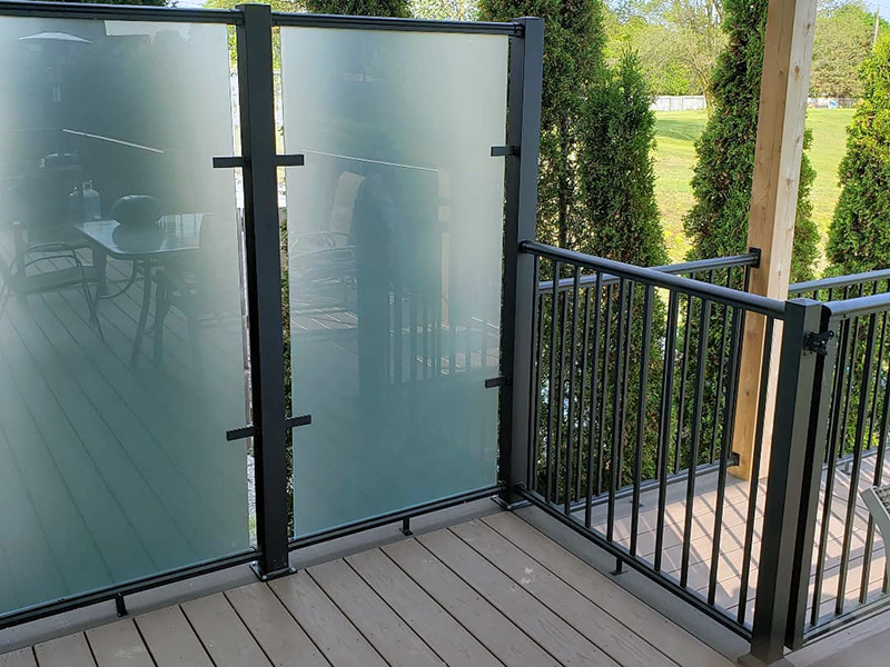 Glass wind wall, aluminum picket railings, and black deck gate by Century Aluminum Railings.